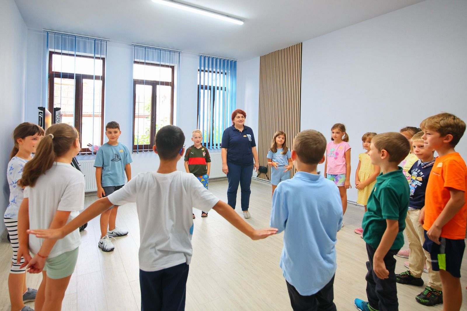 Copii și o coordonatoare Go Science într-un cerc, ținându-se de mâini