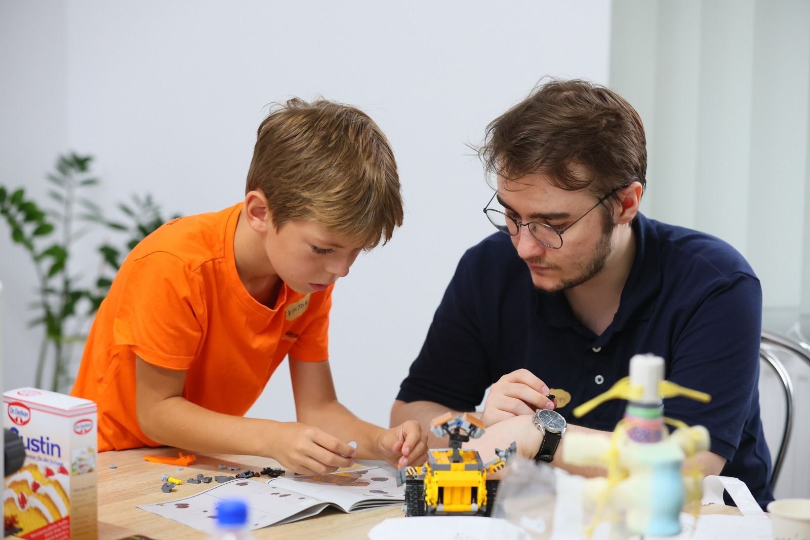 Un copil și un mentor construiesc împreună un robot LEGO