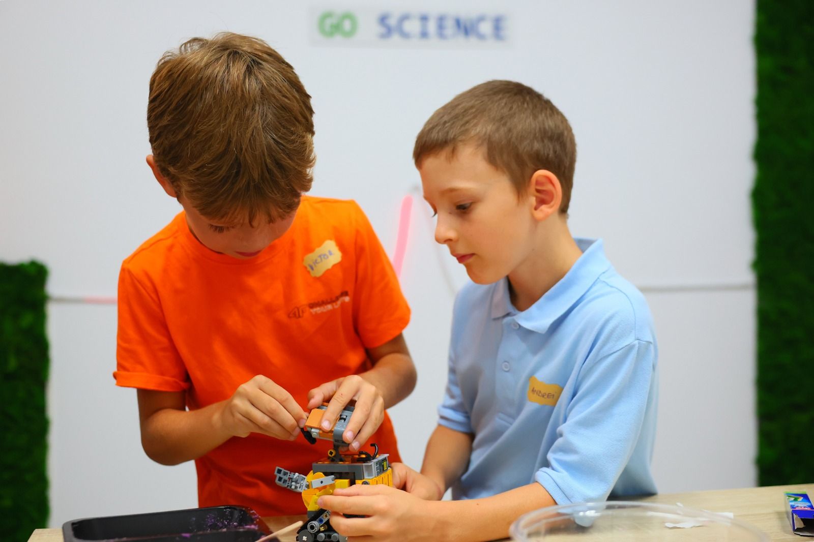 Doi băieți construiesc împreună un robot LEGO